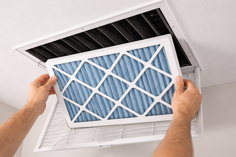 Air vent filter installation in ceiling with hands placing clean HVAC filter